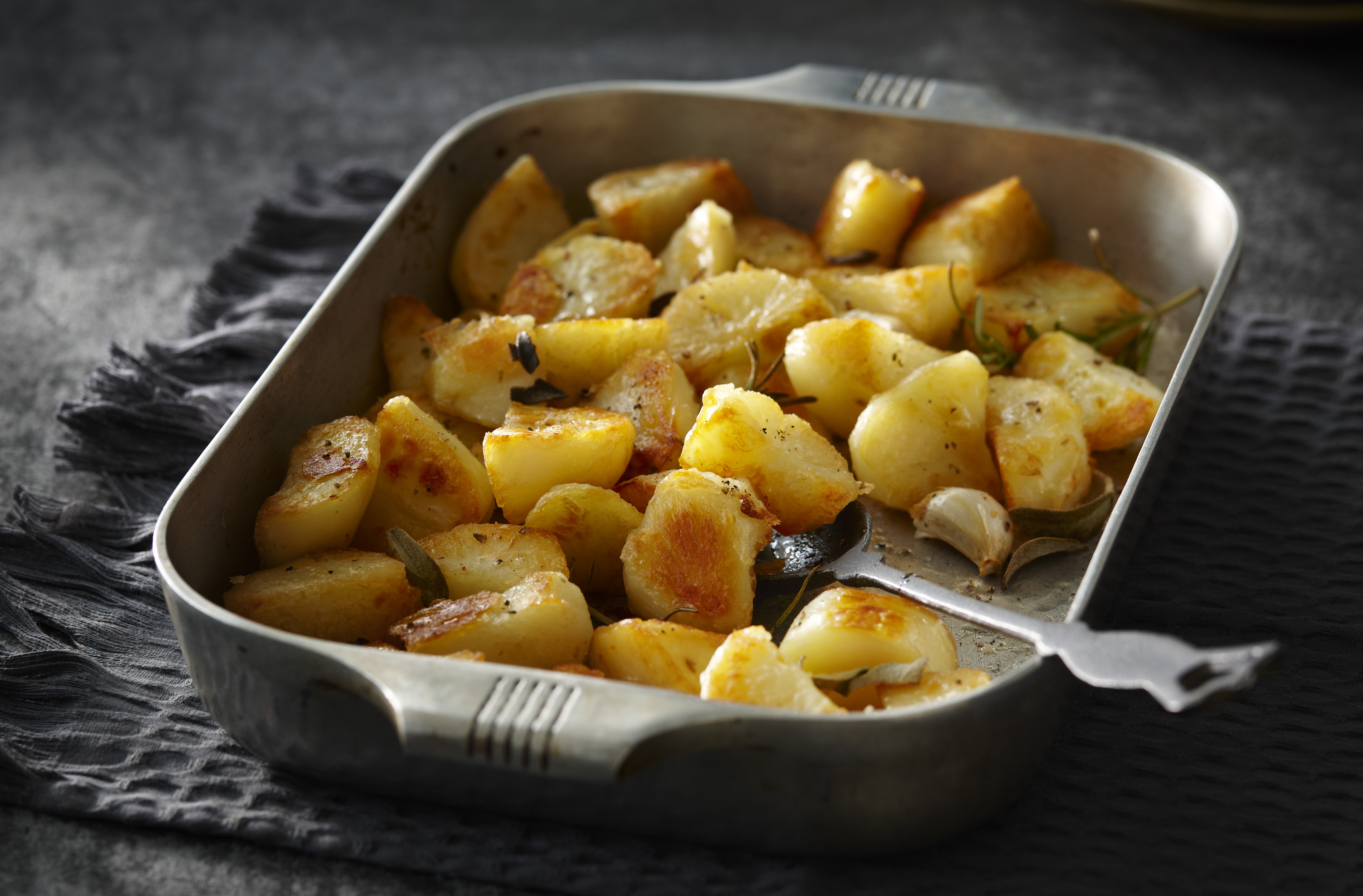A baking pan of golden potato chunks with herbs, slow-roasted in goose fat