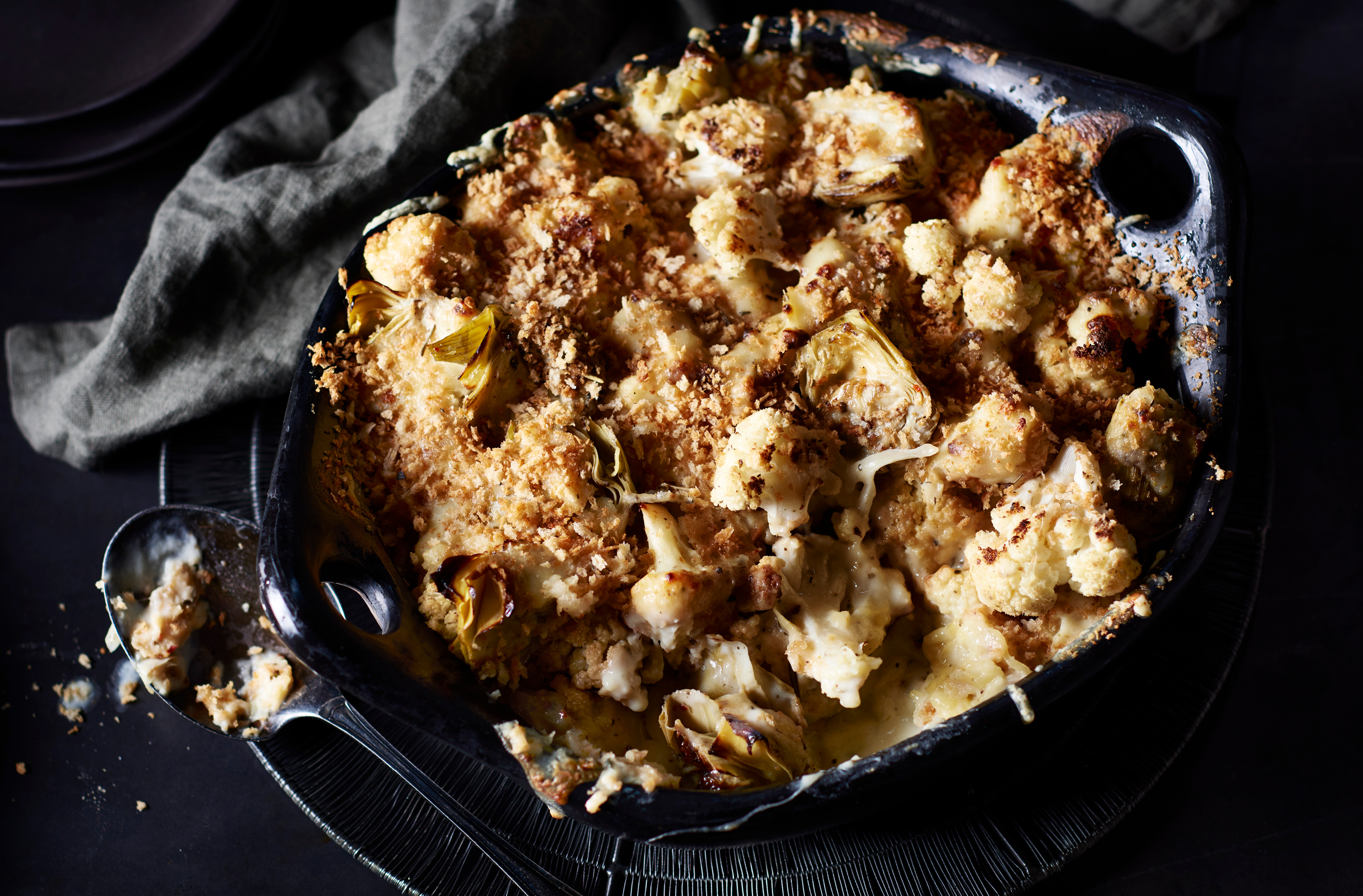 Pieces of cauliflower and artichoke baked with cheese and breadcrumbs 
