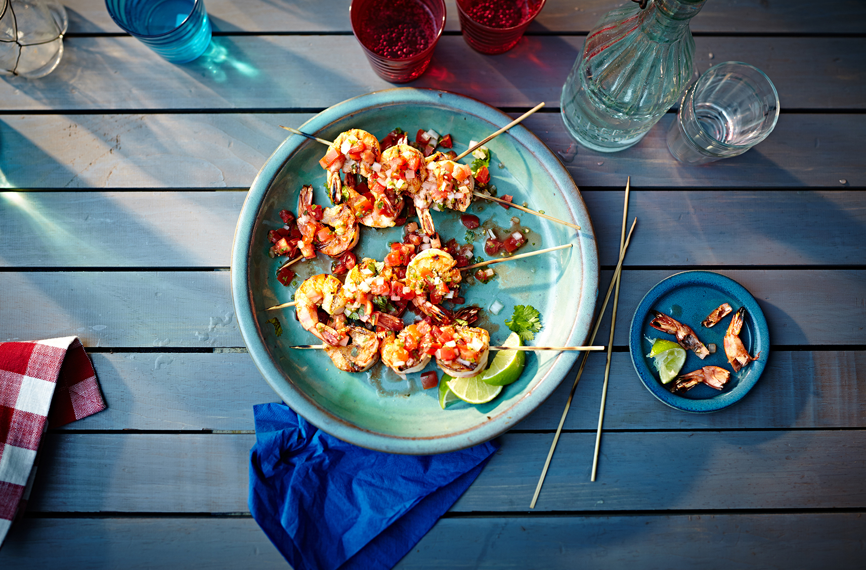 Skewers of grilled shrimp topped with pico de gallo on a plate
