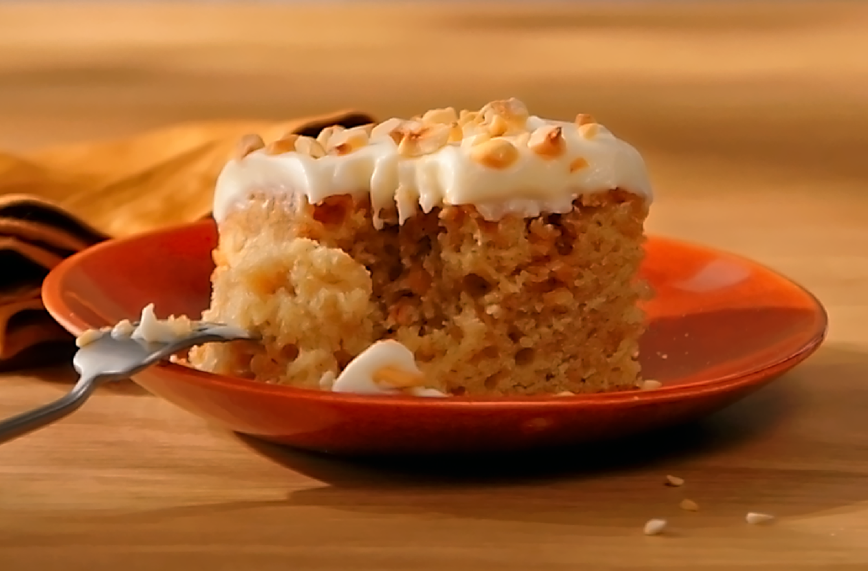 A piece of Coffee & Hazelnut Cake with Whipped Cream Frosting on a dessert plate with one bite eaten