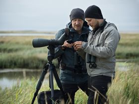 With digiscoping equipment, you can make photos through your spotting scope with your smartphone. Two dedicated birders are looking at their discovery.