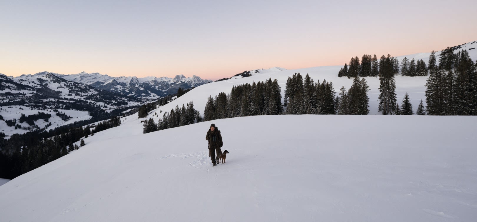 Renate Fahrni - huntress walking in the snowy Swiss mountains with her dog