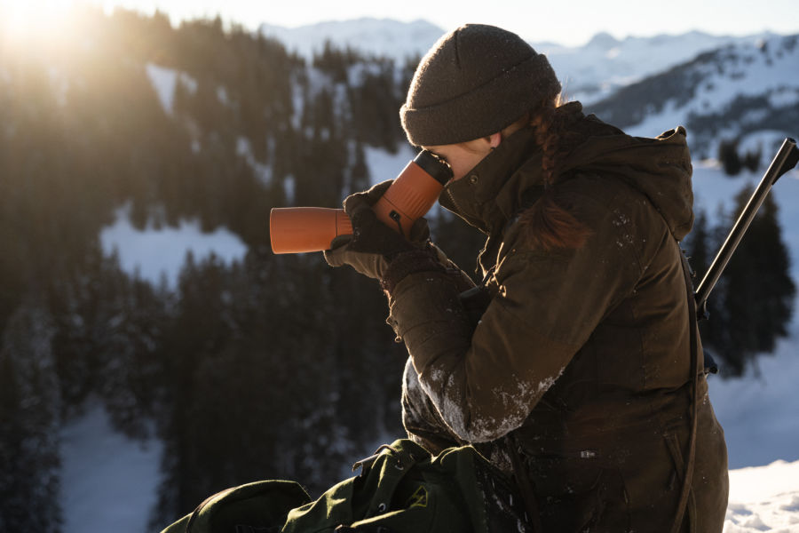 Huntress looking through the SWAROVSKI OPTIK ATC spotting scope in the snowy Swiss Alps 