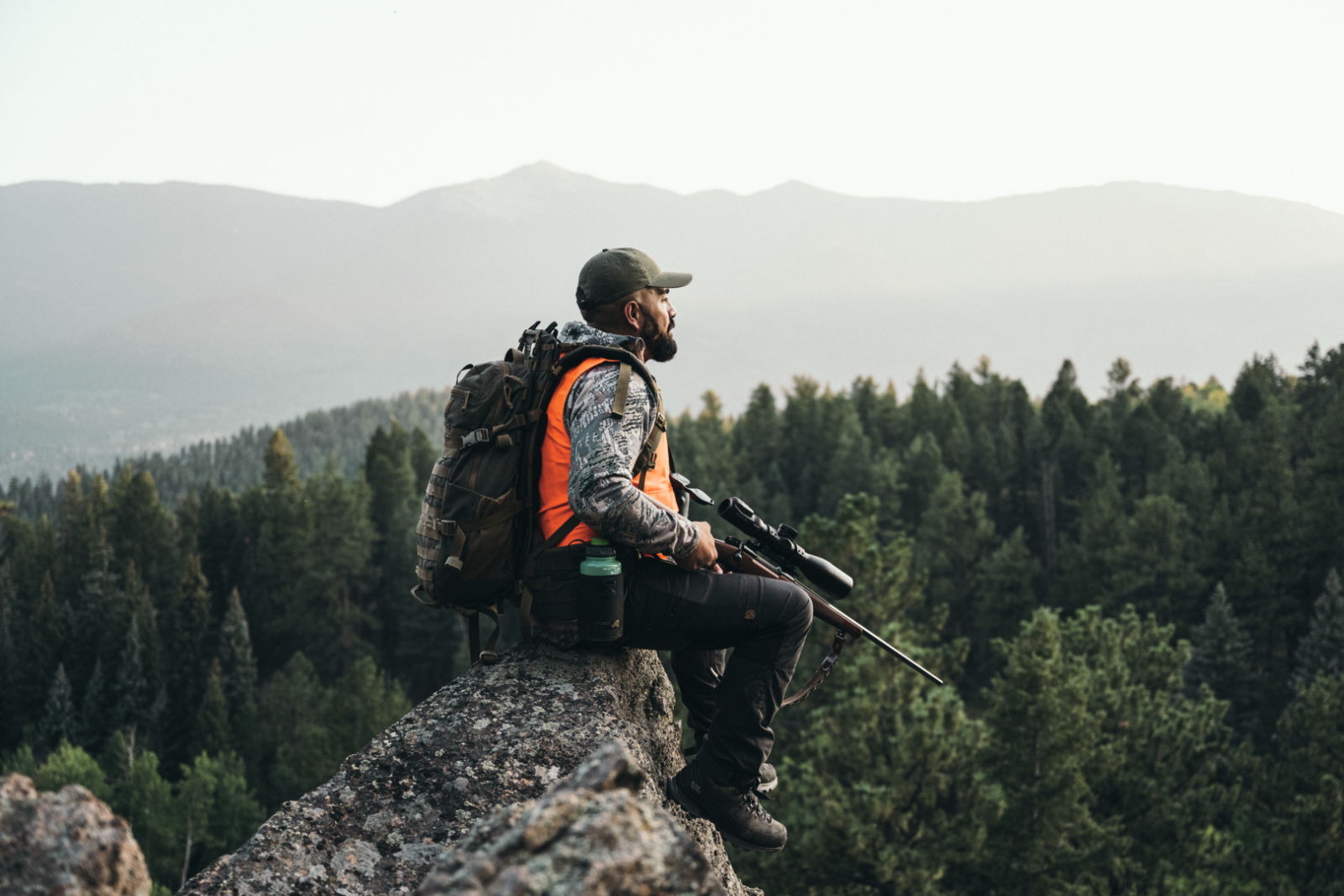 Santino Castellones, Colorado, USA - Man sitting on rocks at the top of a mountain holding the SWAROVSKI OPTIK dS Gen. II in his hands, NL Pure 32 Green