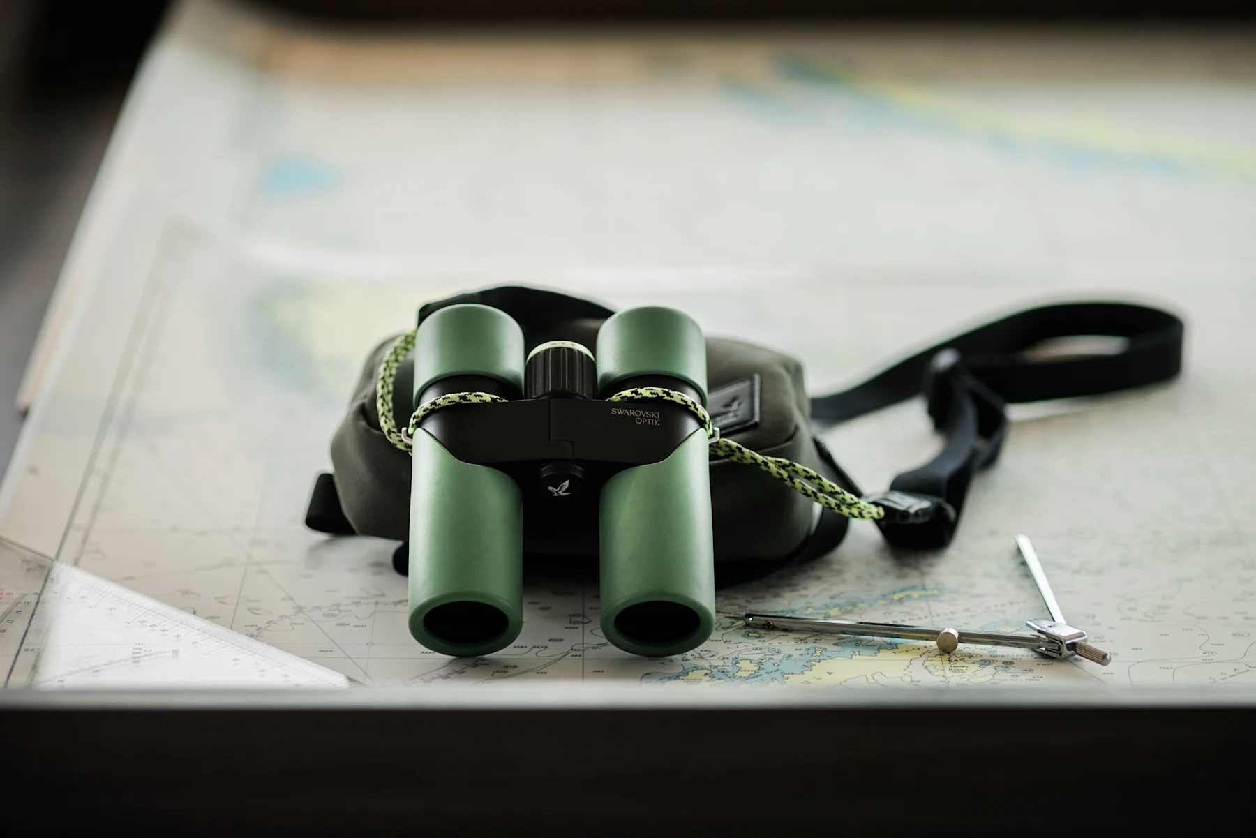 Swarovski CL Companion Mountain Green binocular resting on expedition maps with field bag and strap