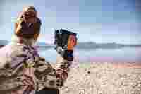 Woman sitting at the lake with the SWAROVSKI OPTIK AX Visio in her hands.