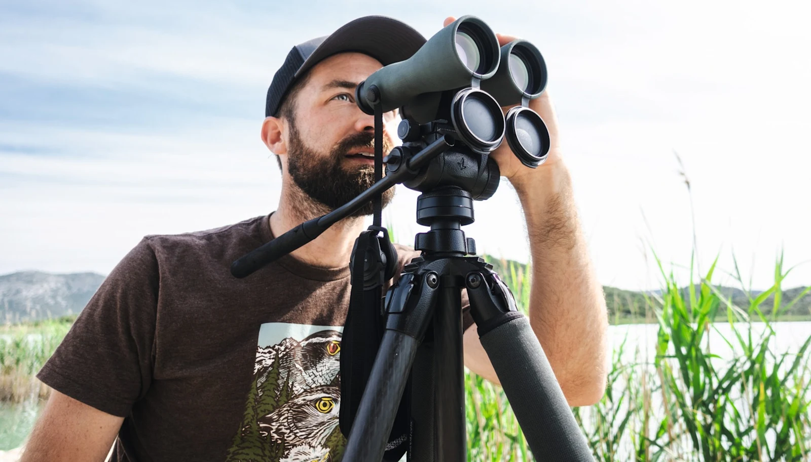 Observer using a Swarovski NL Pure 52 binocular on a tripod beside a lake