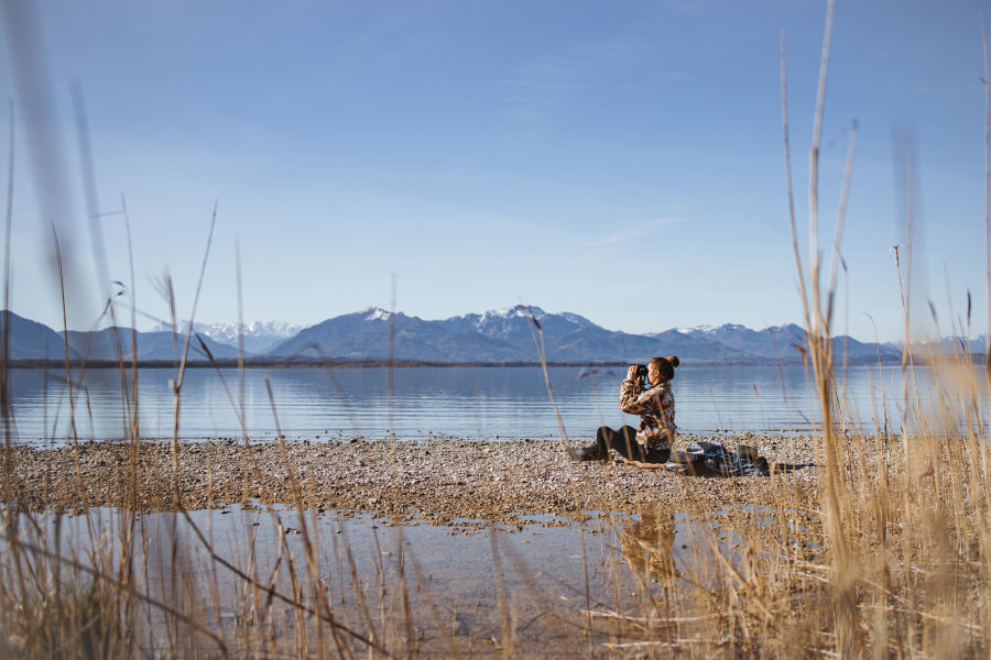 Franziska Consolati sitting at the lake with the SWAROVSKI OPTIK AX Visio Chiemsee 