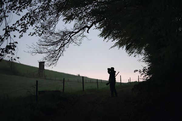 Looking through binoculars while hunting in twilight. 