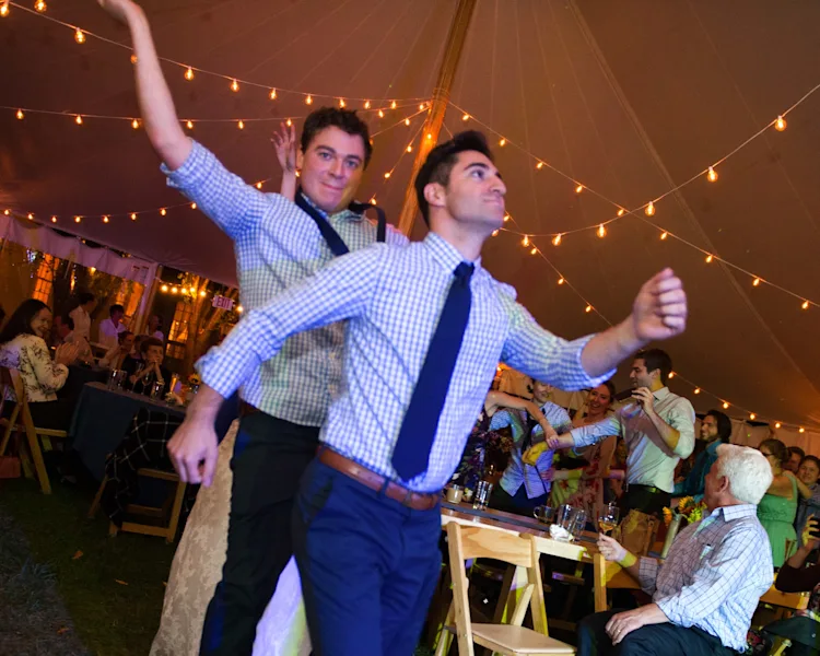 Wedding guests dancing with hands up on the dance floor under the tent at a Shelburne, Vermont wedding reception