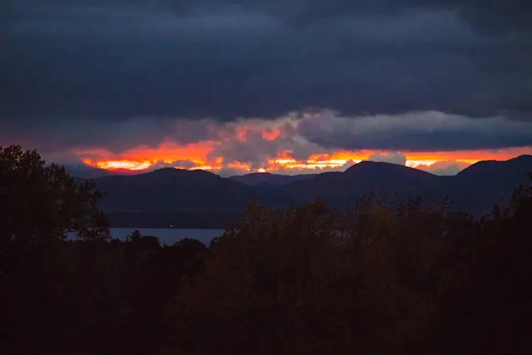 Dramatic orange sunset over the Adirondack Mountains and Lake Champlain viewed from the wedding venue in Shelburne, Vermont
