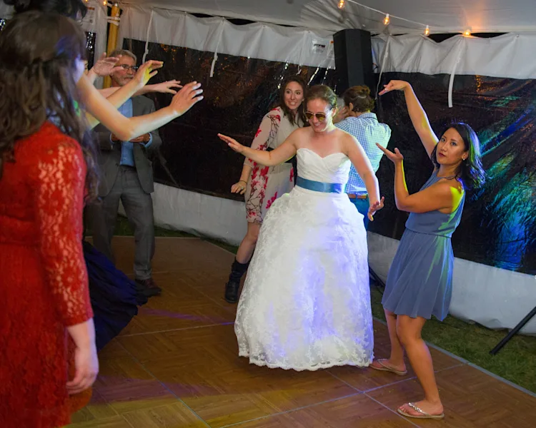 Bride dancing surrounded by friends on the dance floor, everyone going off at a wedding reception in Shelburne, Vermont