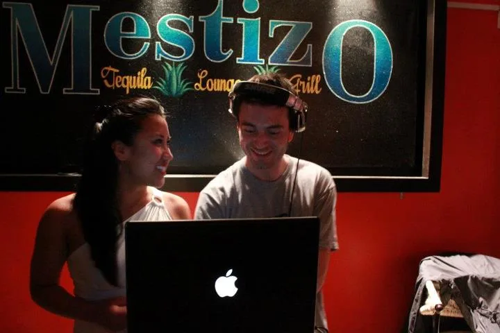 DJ Audeos in headphones at the MacBook decks beside a smiling woman, below the Mestizo Tequila Lounge & Grill sign