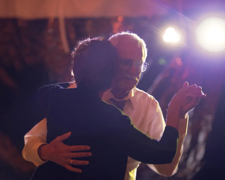 Couple slow dancing together under warm lighting at a wedding reception in Shelburne, Vermont