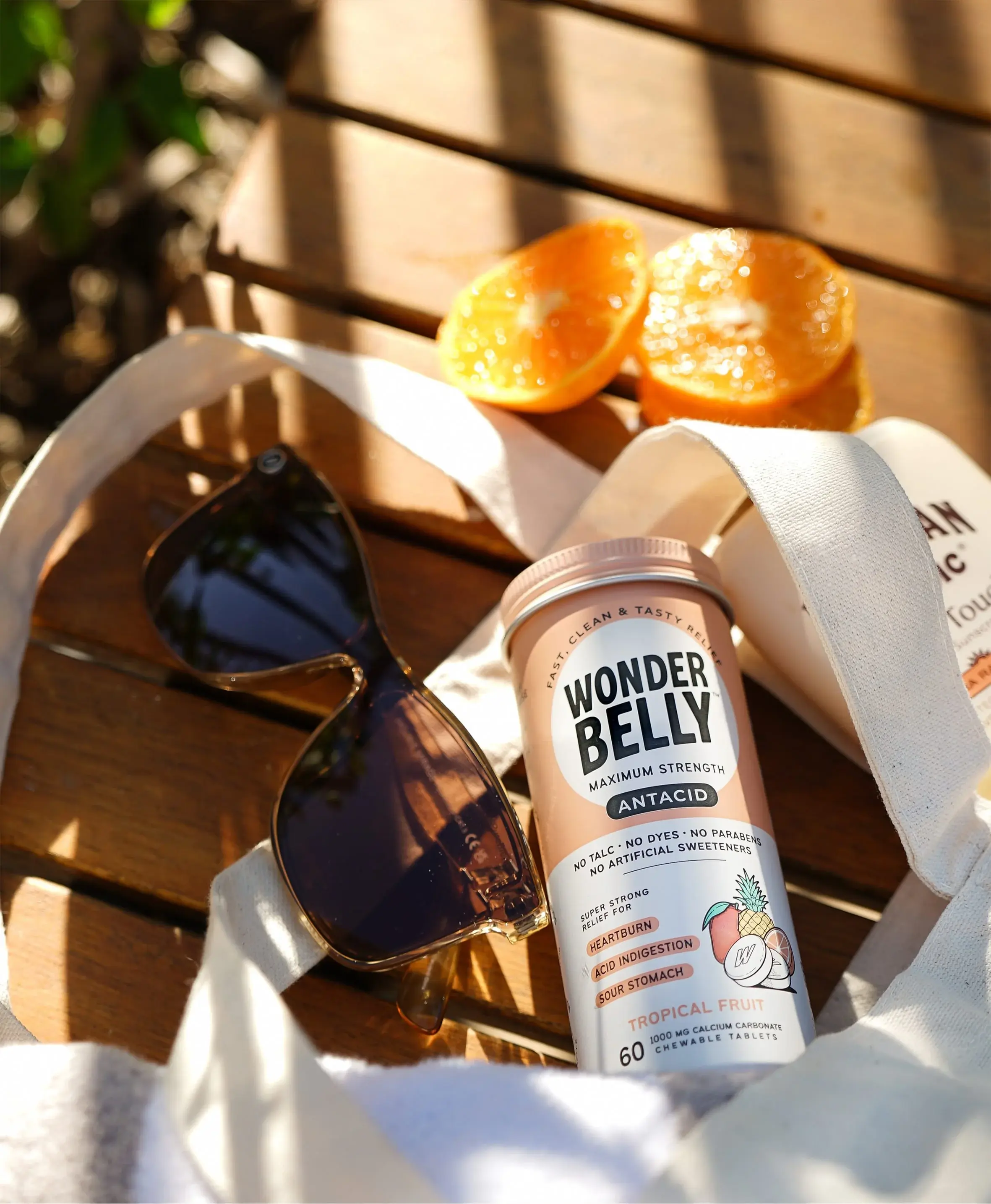 A Wonderbelly maximum strength antacid bottle labeled 120ct “Tropical Fruit,” showing fast and tasty relief for heartburn, acid indigestion, and sour stomach, with illustrated pineapple, mango, and orange on a peach‑colored container.