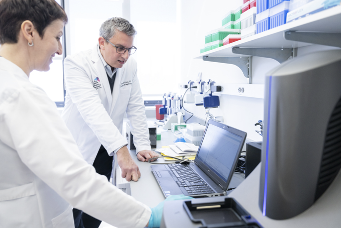 Two researchers looking at results on computer