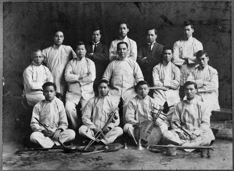 Formal group portrait of musicians wearing similar uniform.
