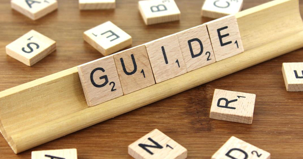 Wooden tiles with letters on them on a stand spelling out the word guide.