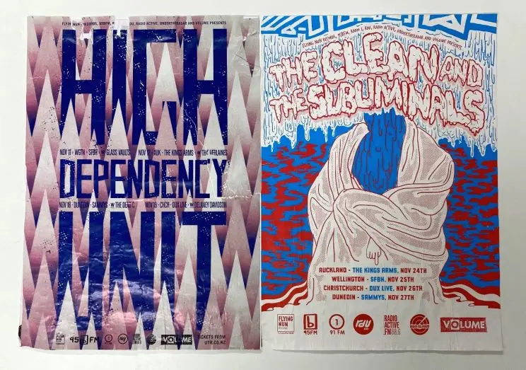 Side-by-side gig posters displayed on a table showing High Dependency Unit on the left and The Clean and the Subliminals on the right. 