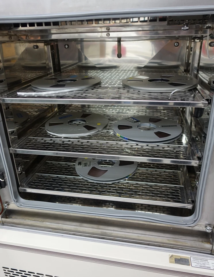 Interior of oven with wire racks on which magnetic tape reels sit ready for being 'baked'.