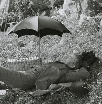 'Mr Murdoch' asleep on the ground, next to an umbrella and a wicker basket, during a picnic at 'Cliffs', Kew, Dunedin.
