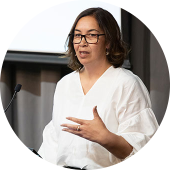 Māori woman standing at a lectern speaking. 