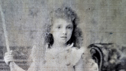 A blurry black and white studio portrait of a young girl in Victorian times.