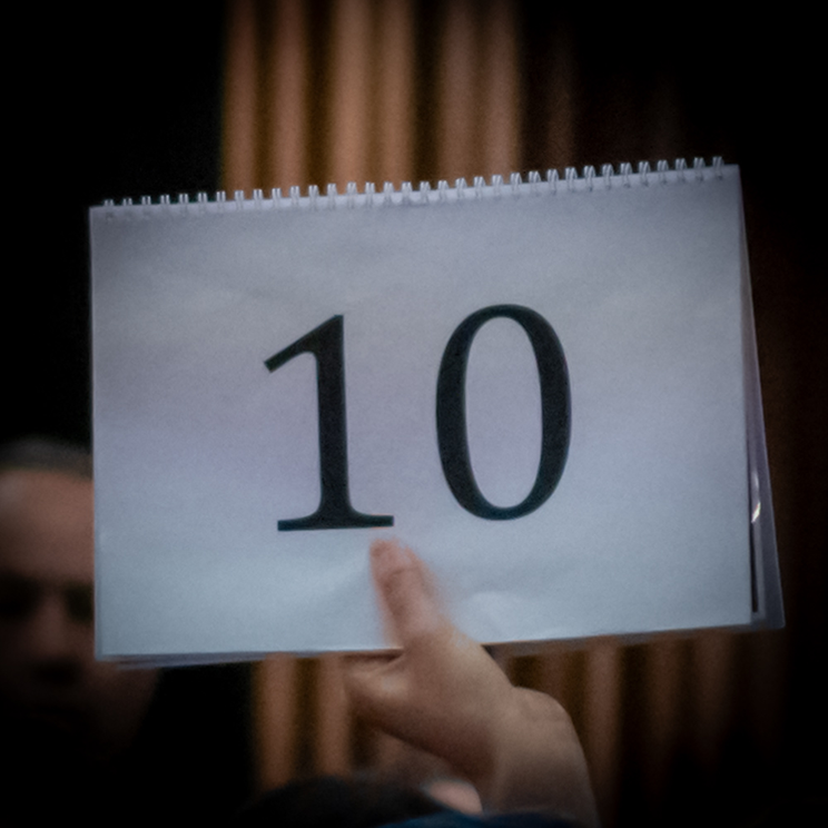 Hand holding up a piece of paper with the number 10 on it. 