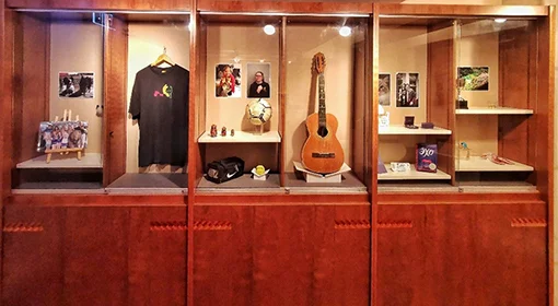 An exhibition display of a t-shirt, a guitar, a football and other items.