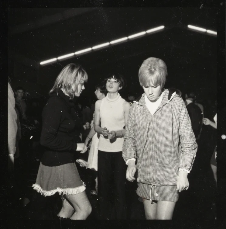 A black and white photo from inside a dance club with young people on the dance floor twisting and moving.