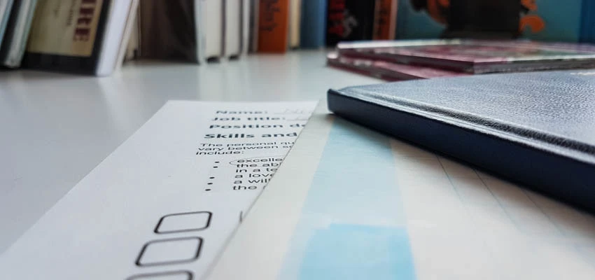 Photo of a job description on a desk under another document and book.