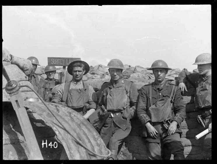 Photograph of First World War soldiers in uniform and helmets, in front of a trench they've signposted 'Surrey Lane'.