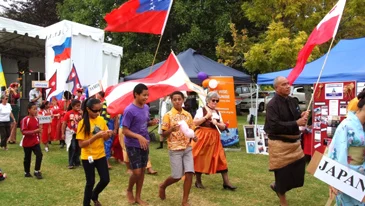 People from Pacific countries holding flags or signs with their country's name parading in a multicultural festival event