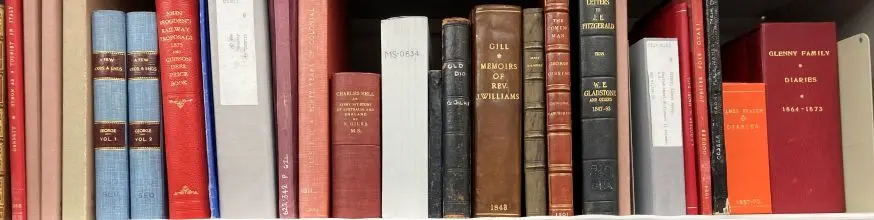 A row of bound books sit in a row on a shelf.