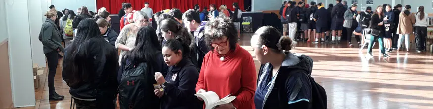 People in a big hall looking at books. 