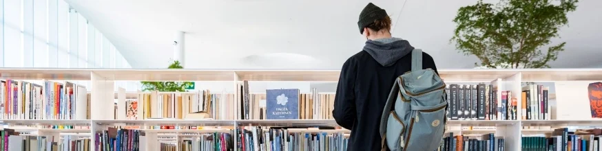 Person browsing bookshelf in a library.