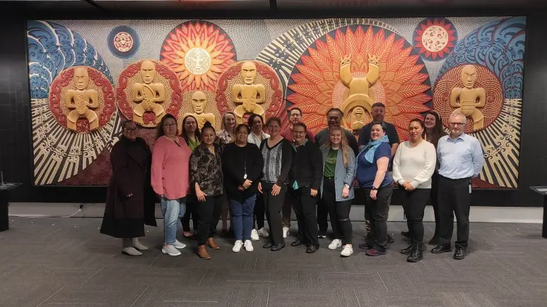 A group of people standing in front of a mural.