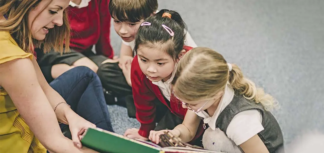  A teacher reading a book to a group of students.