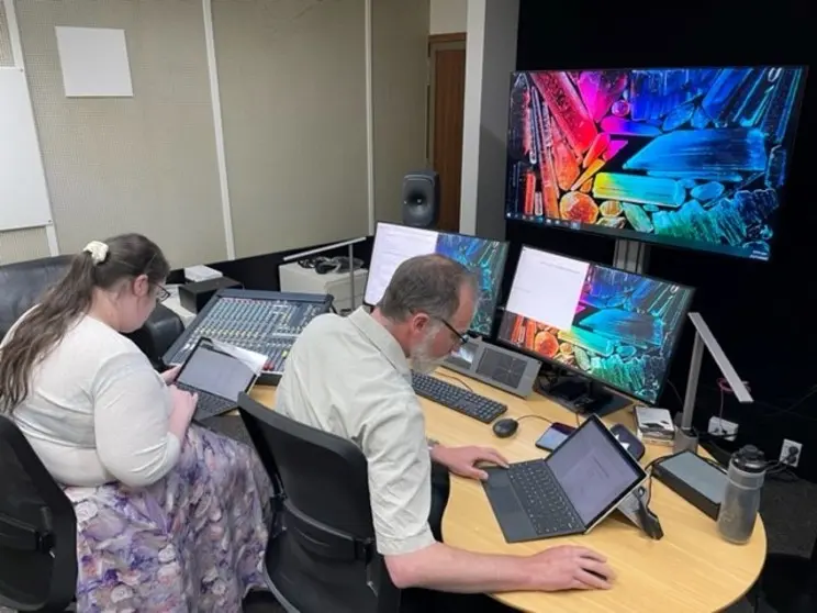 A man and a woman using laptops at a desk.