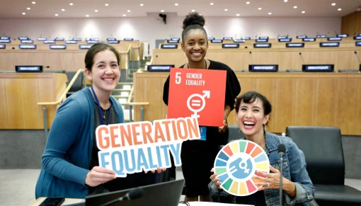Young women hold SDG and Generation Equality signage.