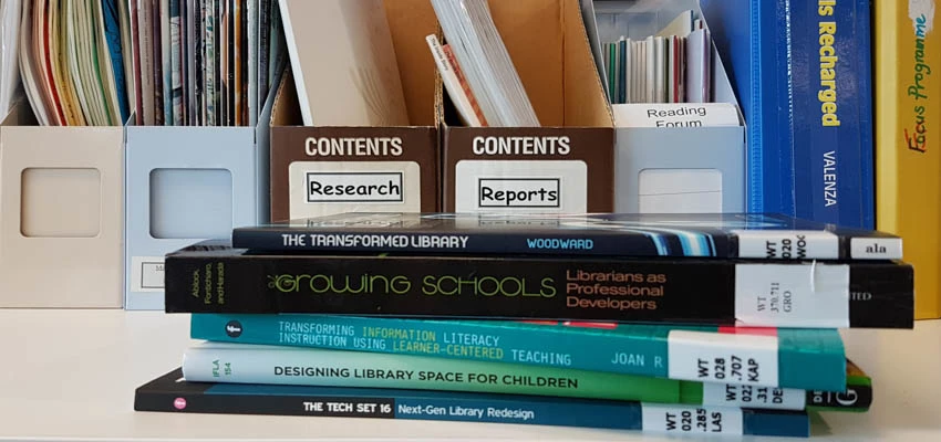 Desk with books on library trends and research.