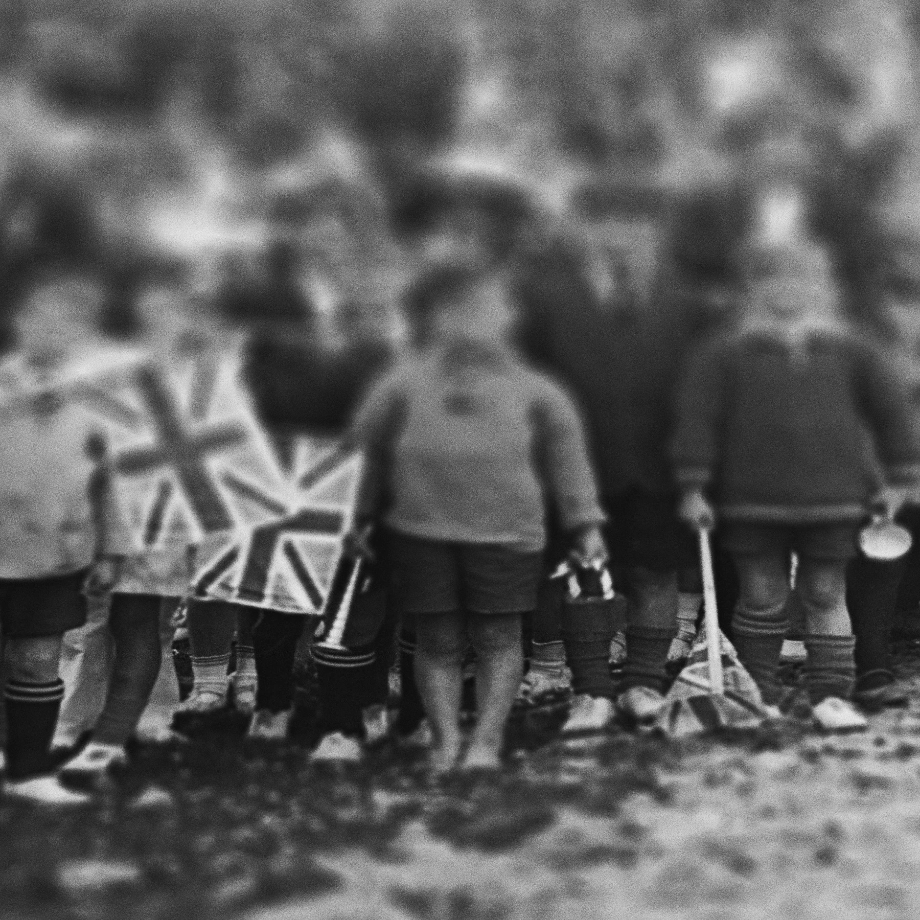 Children holding small flags are grouped together watching something off camera.