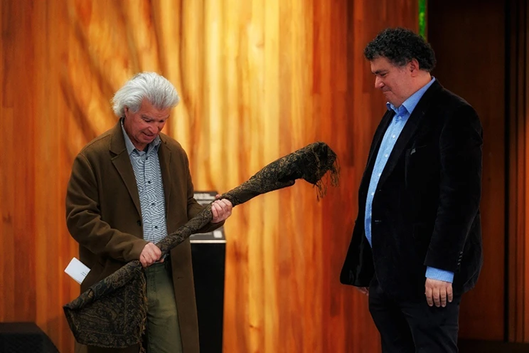 Person receiving a tokotoko (carved ceremonial staff) during a presentation ceremony.