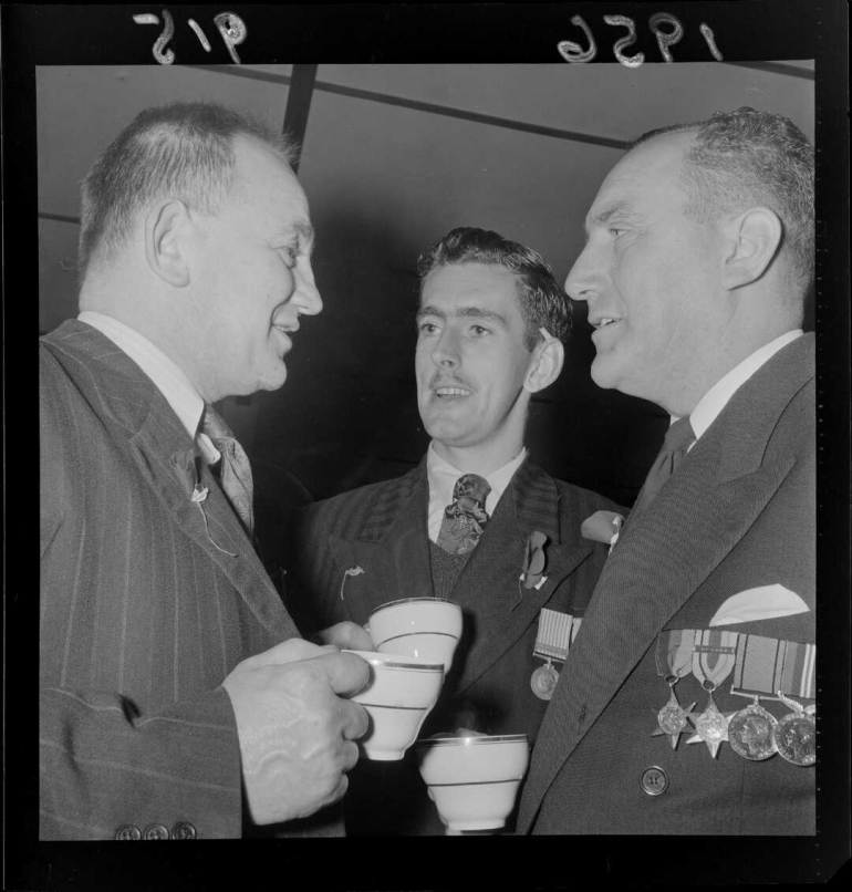 Unidentified veteran soldiers talking face to face while holding teacups after the Anzac Day dawn parade.