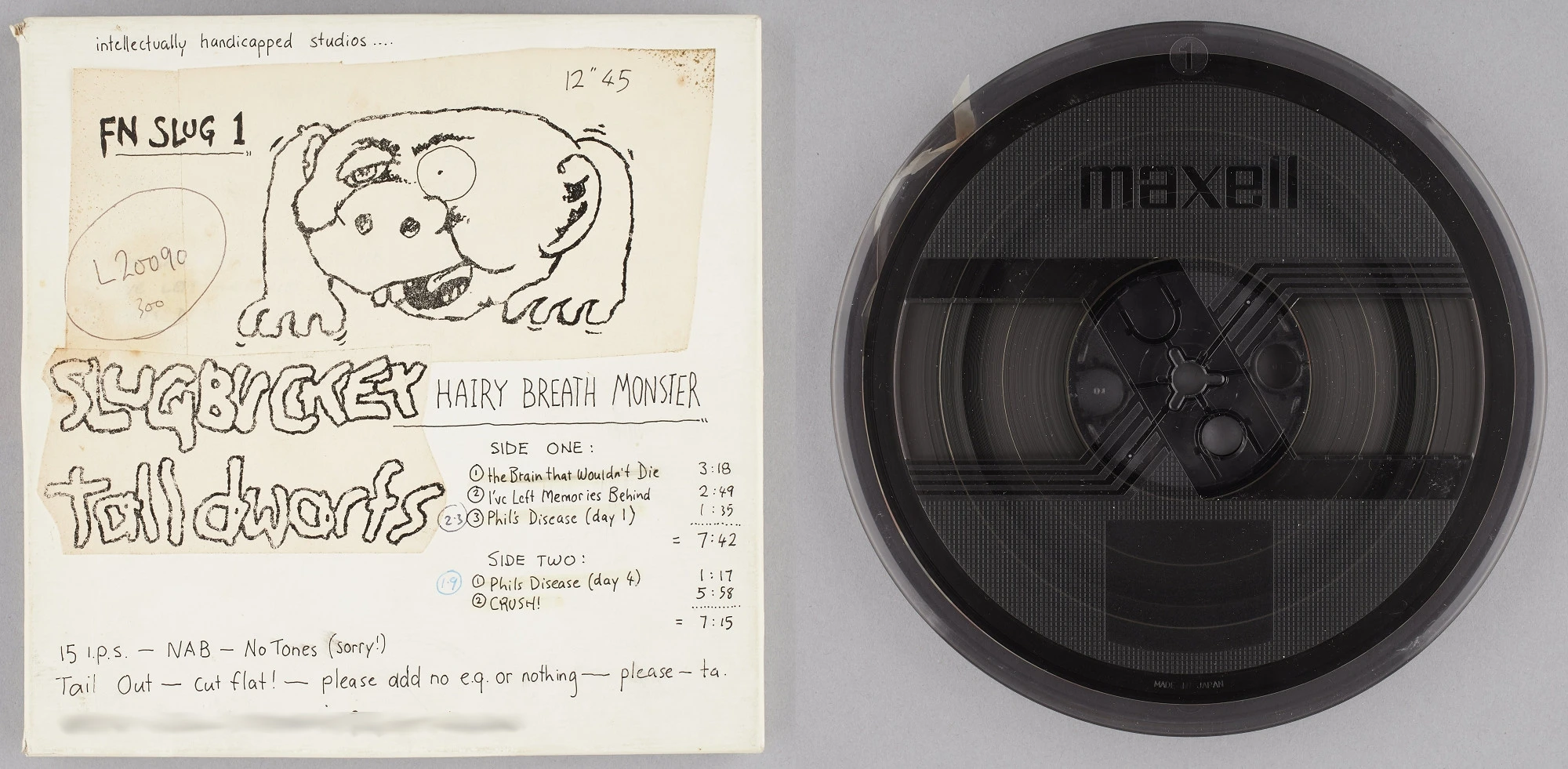 A reel-to-reel tape next to its container with written notes to mastering engineer and track list along with a drawing of a monster-shaped creature with a head and long arms. 