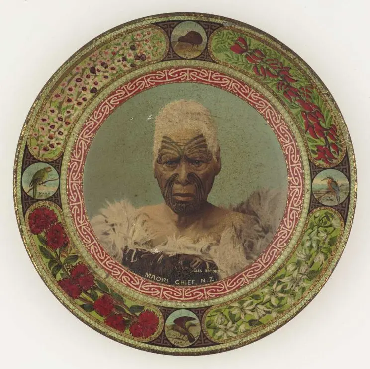 Shows a head-and-shoulders portrait of the Ngāti Maru chief Matene Te Nga. He shows his distinctive facial moko and wears a kahu huruhuru (feather cloak). The portrait is encircled by a band of kōwhaiwhai. The outer edge of the plate is decorated with four native birds, at twelve, three, six and nine o'clock respectively: the kiwi, the kōtare (kingfisher), the kea and the kākā. There are also decorations of native plants: kōwhai (kakabeak), pikiareko (clematis), rātā and mānuka.