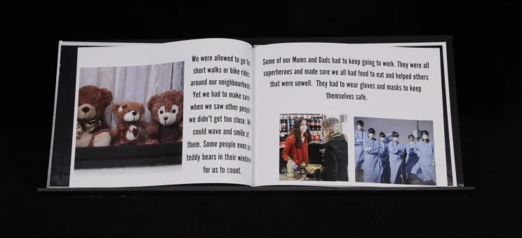 An open book with text and images of teddy bears, people in masks and a group in PPE.