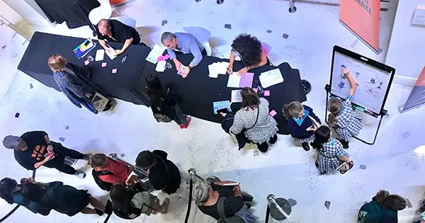 Aerial photo looking down at people getting books signed by 3 writers at the Auckland Writers Festival.