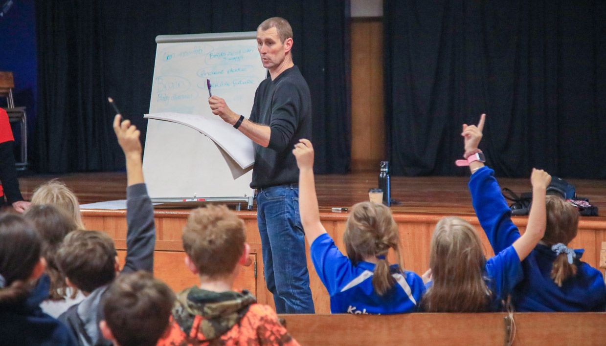 Te Awhi Rito New Zealand Reading Ambassador Alan Dingley in front of a group of students.