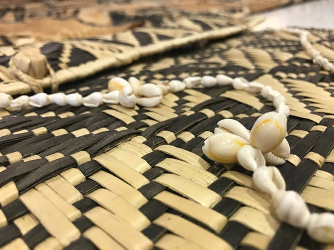 Woven mat and shell necklace.
